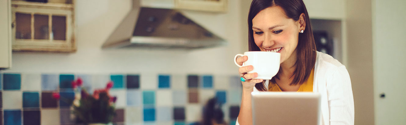 Young woman using tablet while drinking coffee
